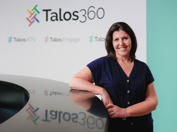 Janette Martin smiling and standing in front of the Talos 360 logo.